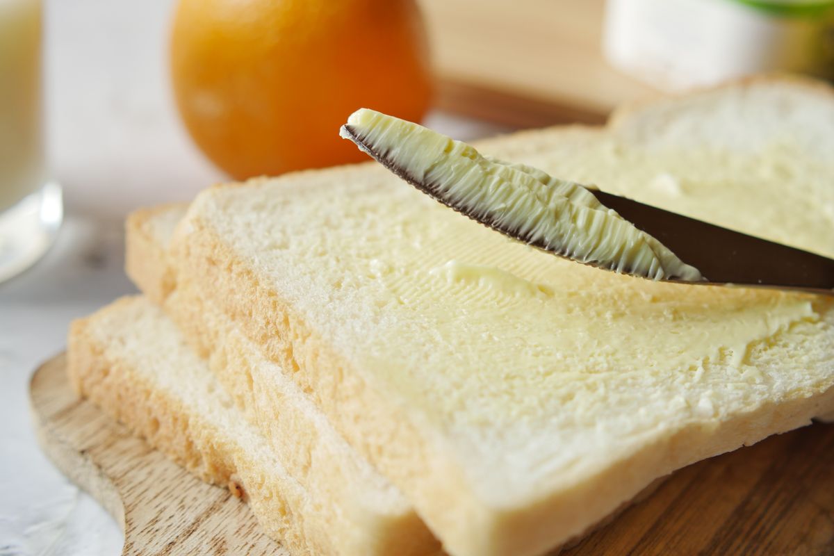 A golden pat of butter melting on a warm slice of toast, with a soft-focus kitchen background.
