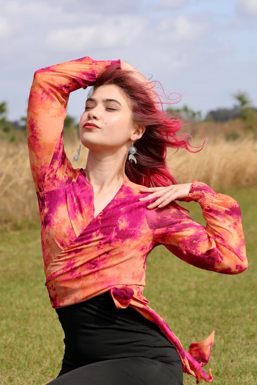 Beautiful Woman in a Colorful Blouse Sitting in the Meadow 