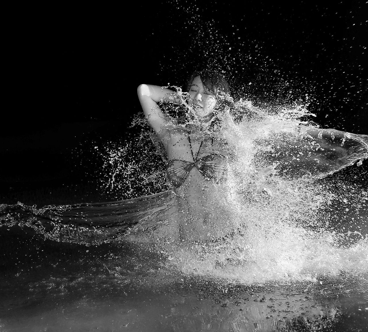 engaging black and white photo of a woman experiencing a joyful splash