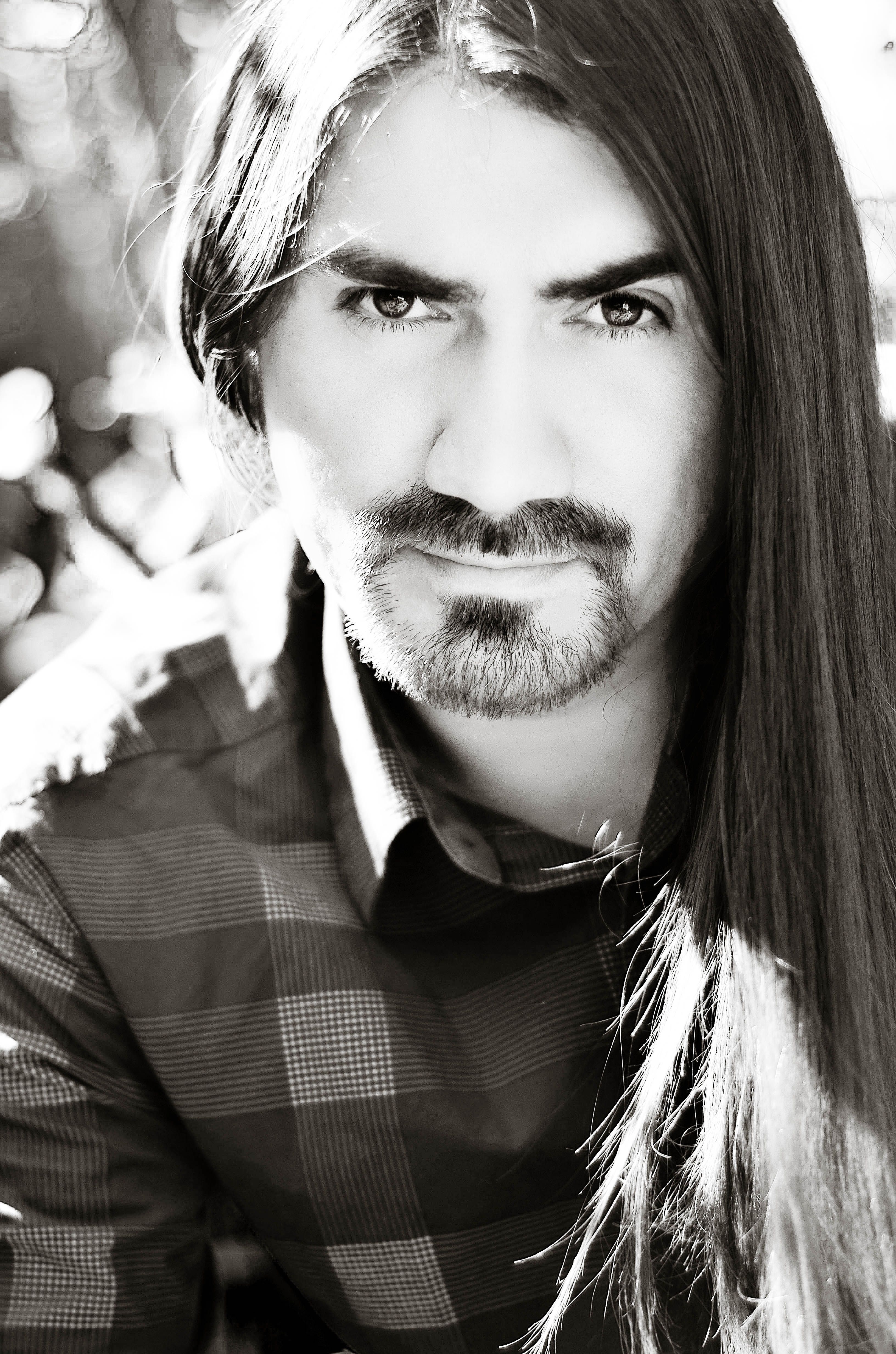 Striking black and white portrait of a long-haired man with intense gaze.
