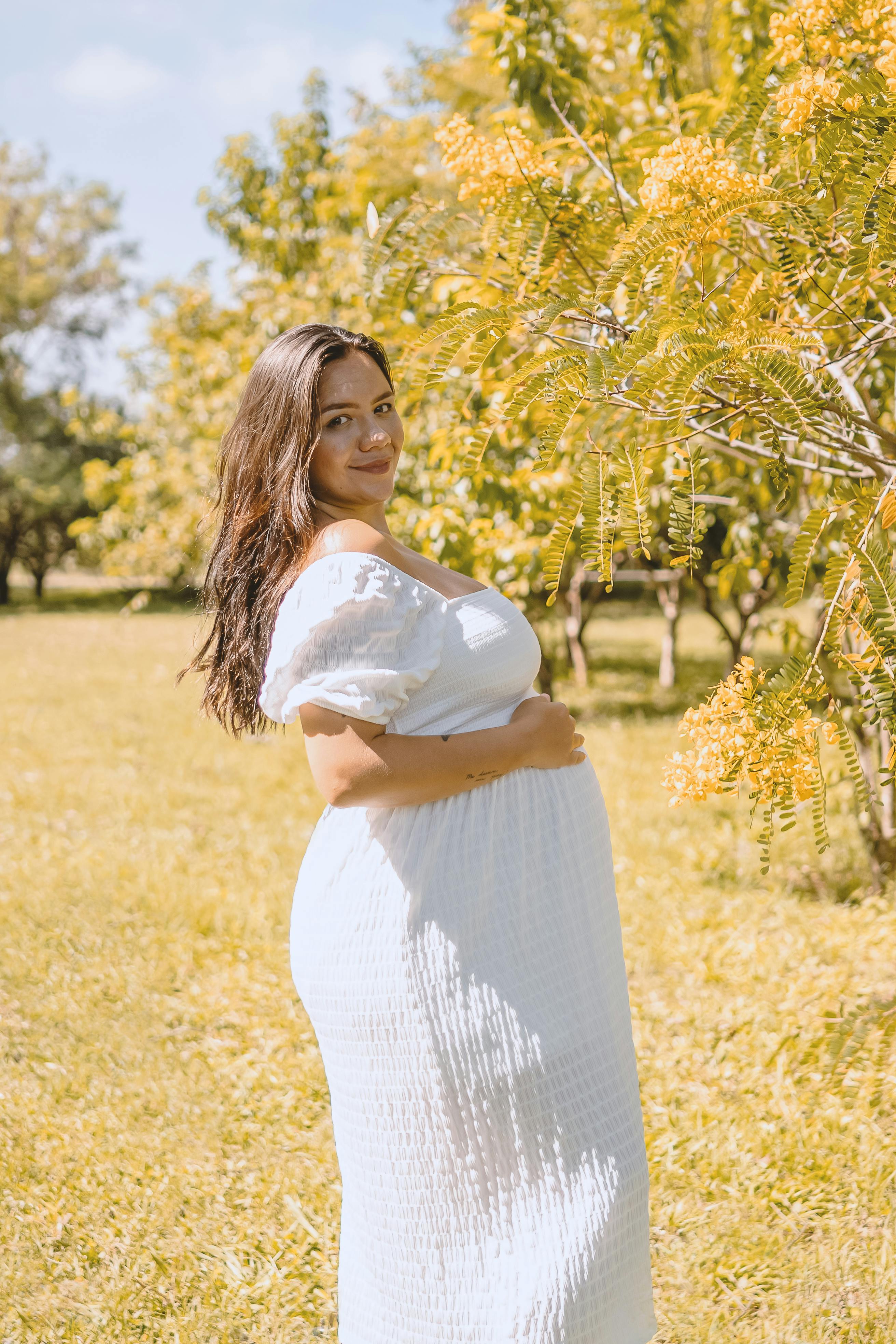 pregnant woman posing in garden with trees