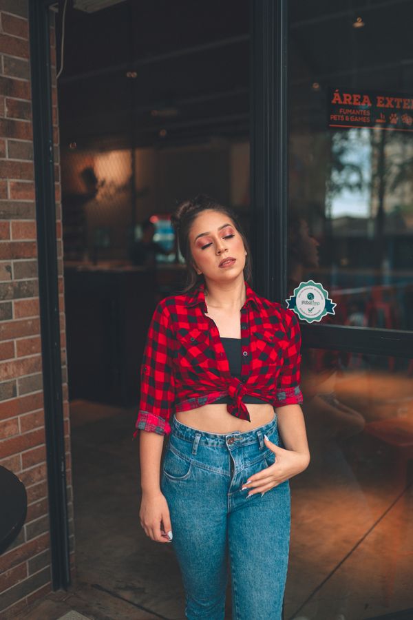 woman wearing flannel shirt over crop top and jeans
