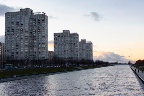 Free A serene cityscape featuring tall residential buildings by a river during twilight. Stock Photo