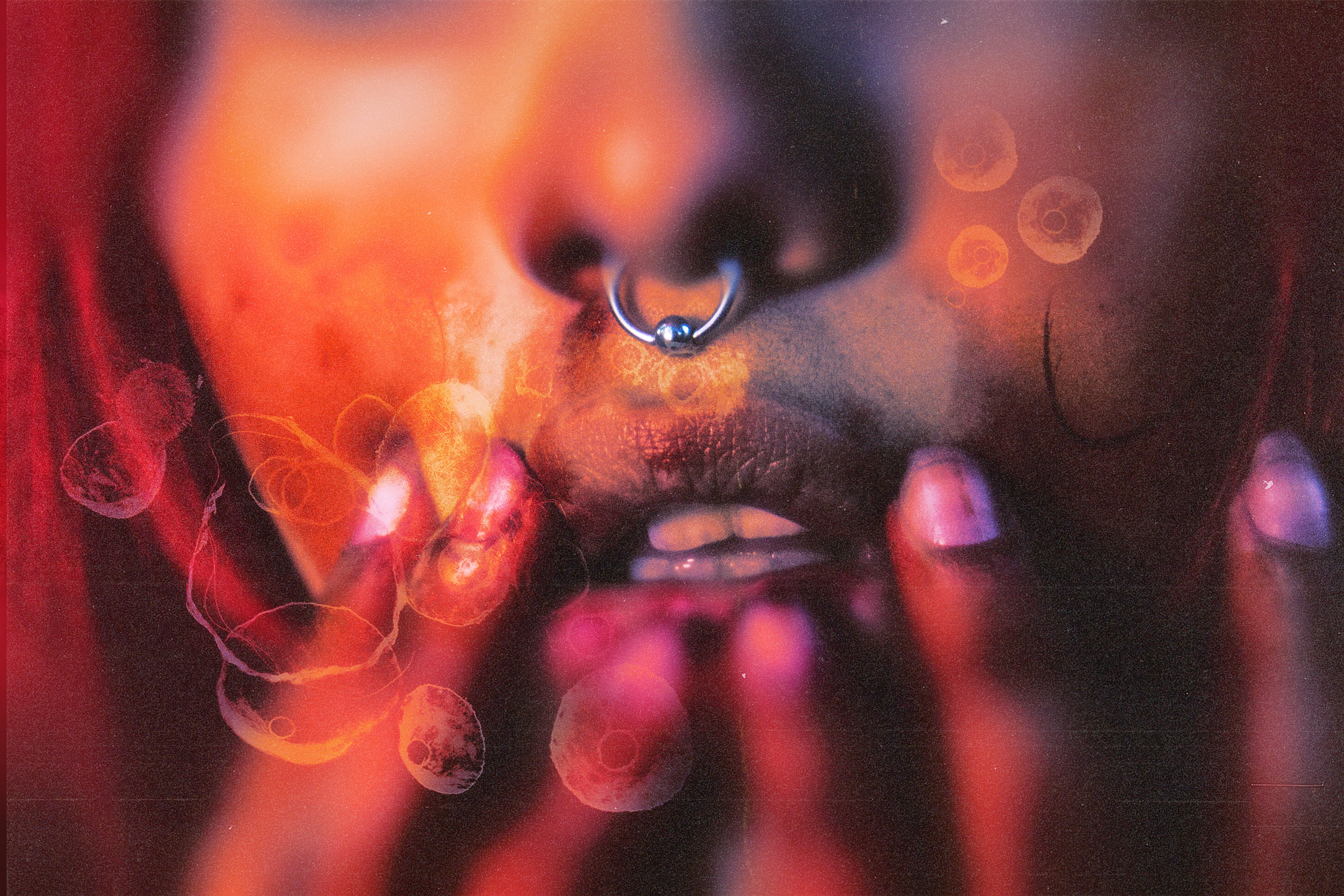 Close-up image of a face with piercing and hands, featuring artistic overlays and warm tones.