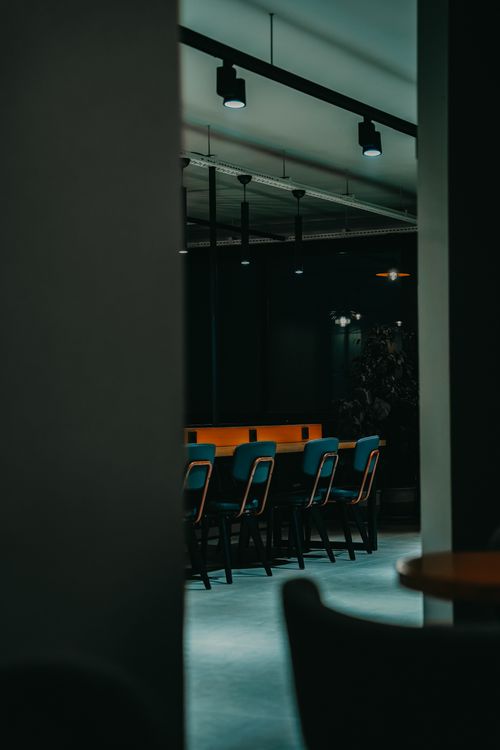 Free A contemporary dining area with stylish chairs under dim lighting, creating a cozy ambiance. Stock Photo