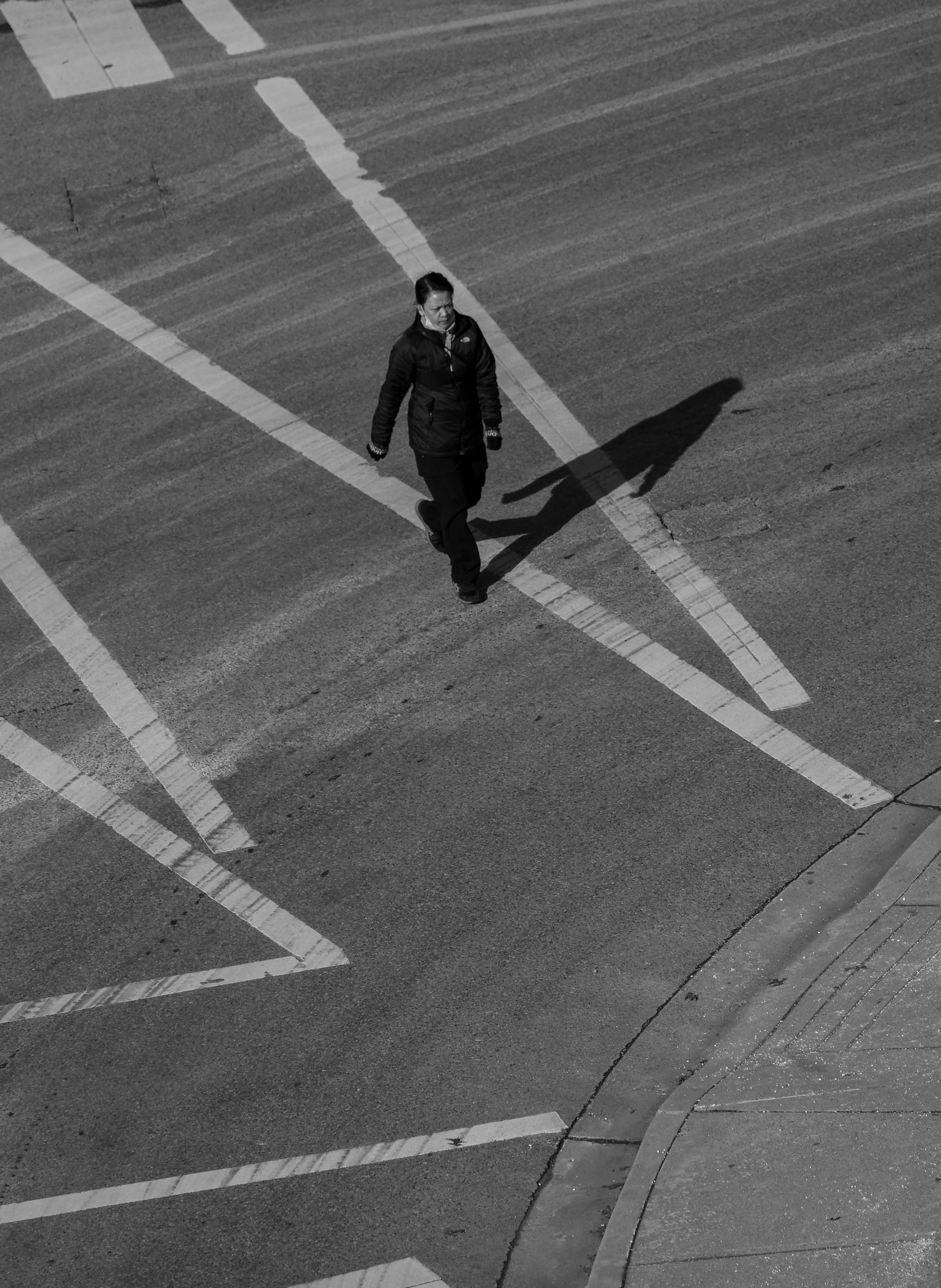 A person walking across a crosswalk in black and white · Free Stock Photo