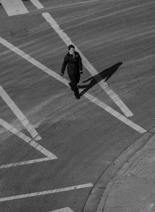 A person walking across a crosswalk in black and white