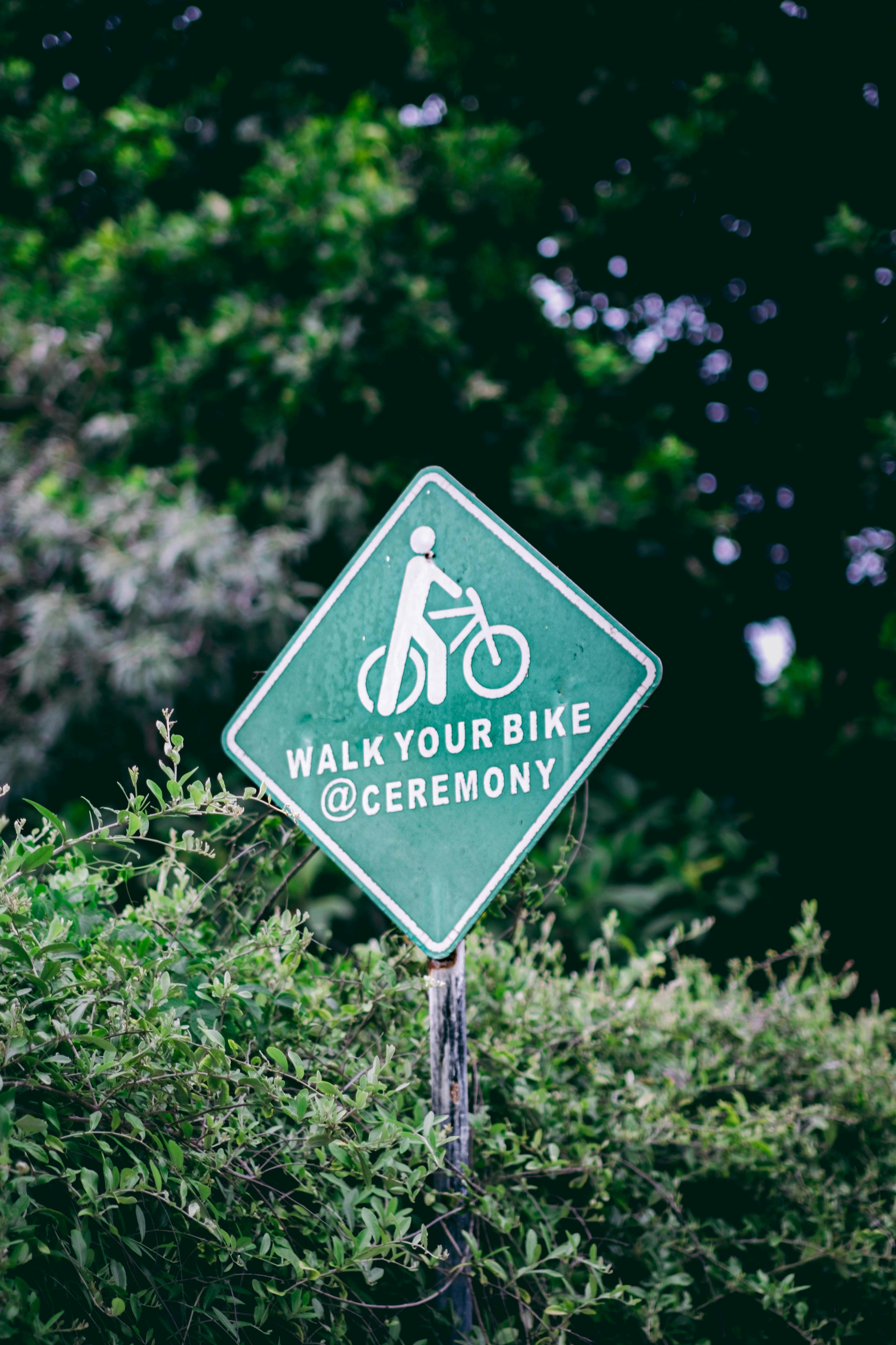 A 'Walk Your Bike' sign surrounded by tropical greenery in Bali, Indonesia.