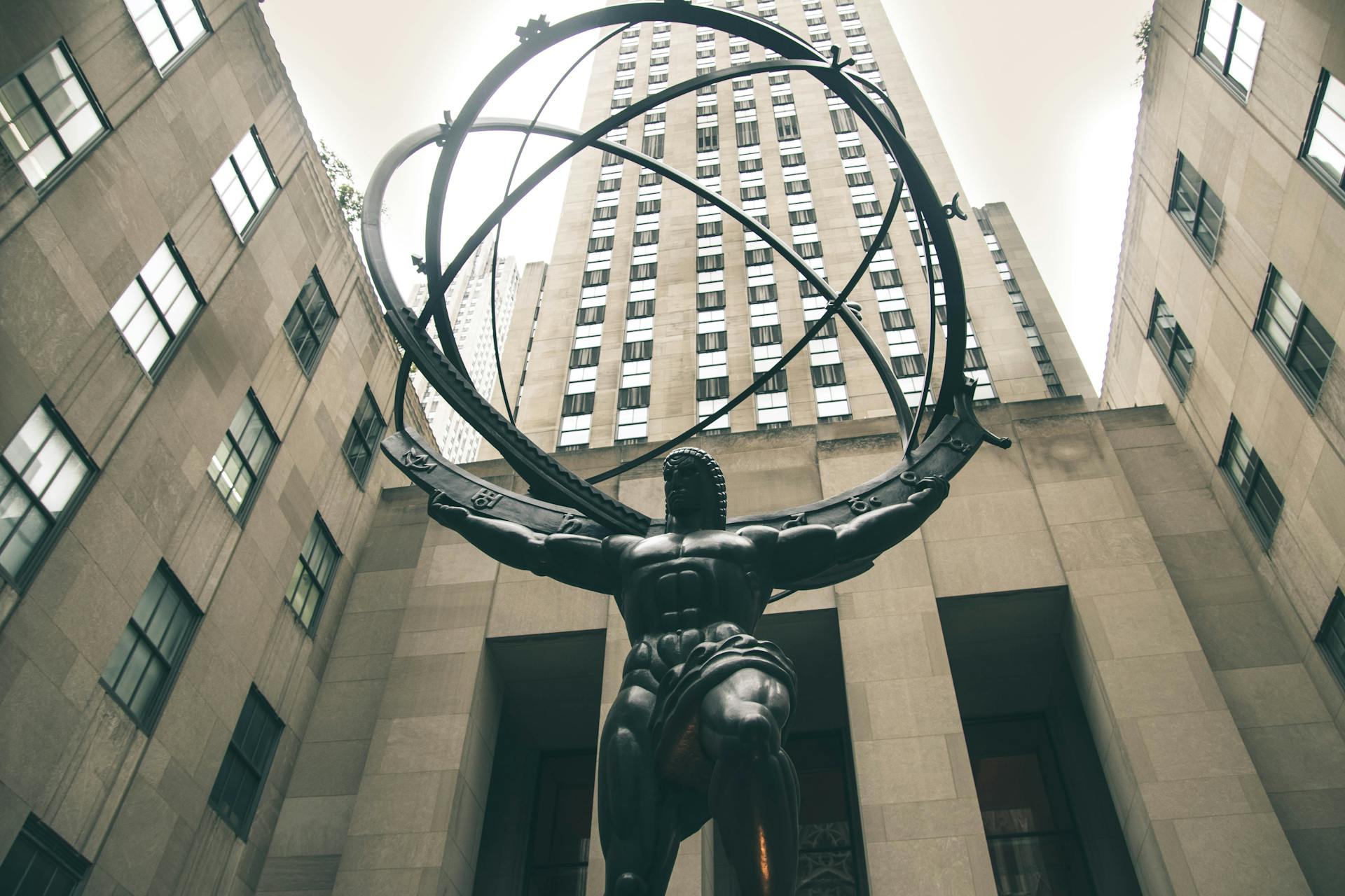 Low angle view of Atlas statue with skyscrapers at Rockefeller Center, New York City.