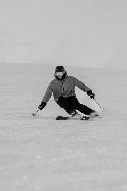 A skier gracefully carves through fresh snow, showcasing skill and speed in a winter sports setting.