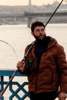 A young man enjoys fishing by the Bosphorus Bridge in Istanbul, Turkey.