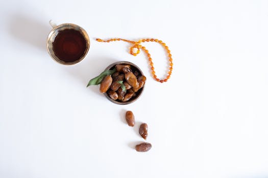 Delightful top view of a cup of tea, dried dates, and a necklace on a white background.