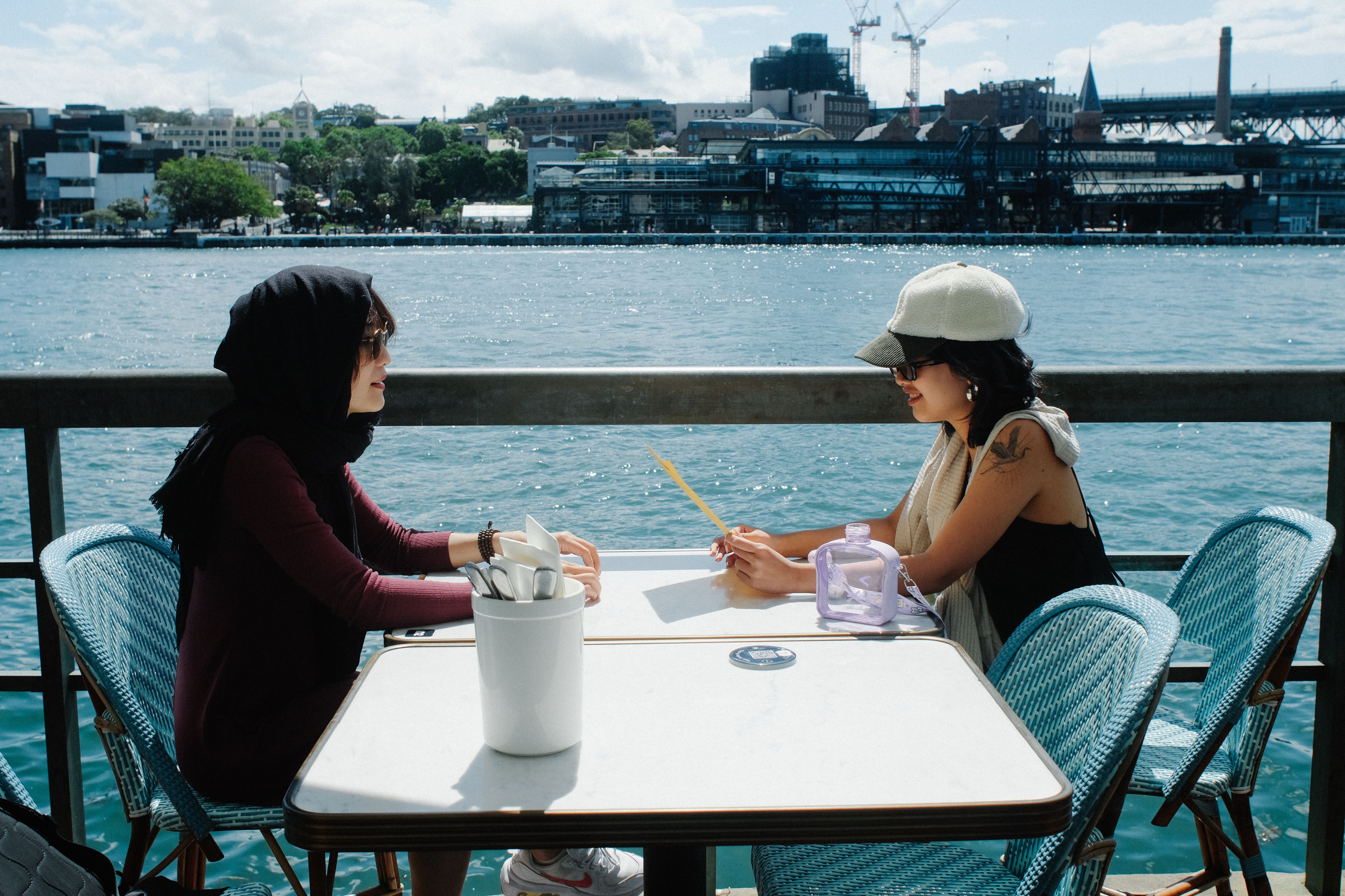 Two women enjoying a sunny day chat by the Sydney Harbor waterfront, NSW, Australia.