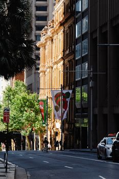 A vibrant street in Sydney featuring historic and modern architecture under bright sunlight.