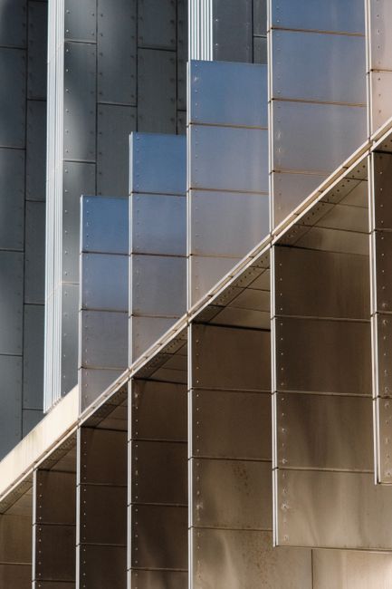 Close-up of a modern metal building facade with vertical lines and reflections.