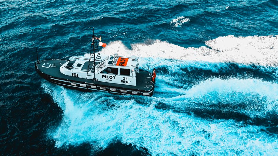 Dynamic aerial shot of a pilot boat cutting through the ocean waves, showcasing marine transport.