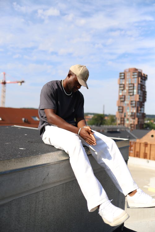 Man Sitting on Wall and Looking Down 