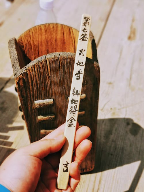 Person Holding a Wooden Stick with Japanese Symbols 