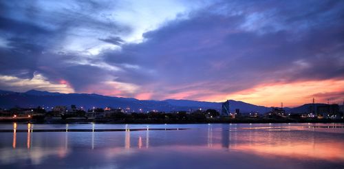 Free Breathtaking twilight view of city skyline with colorful sky reflecting over calm waters. Perfect for serene urban scenes. Stock Photo