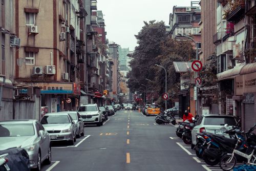 Free A city street lined with parked cars and residential buildings on an overcast day. Stock Photo