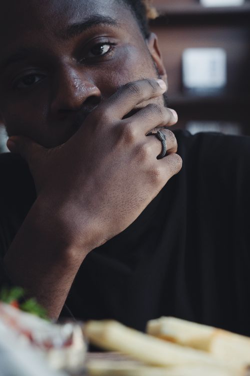Free Close-up portrait of a man thoughtfully resting his hand on his face, highlighting a ring on his finger. Stock Photo