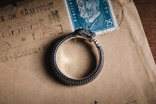 Close-up of a vintage snake ring on an aged envelope with a postage stamp.