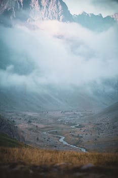 A breathtaking view of foggy mountains with a winding river in a tranquil valley.