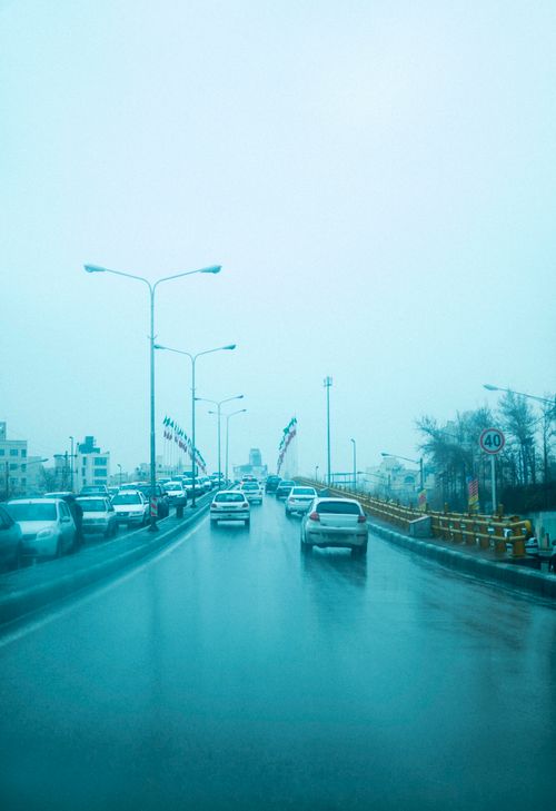 Free Traffic on a wet city street with overcast skies, showcasing urban life on a rainy day. Stock Photo