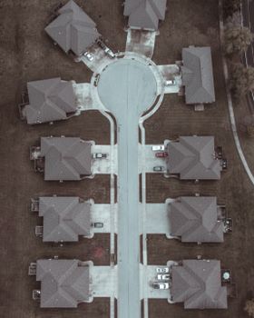 Aerial shot of a suburban cul-de-sac with identical houses and parked cars.