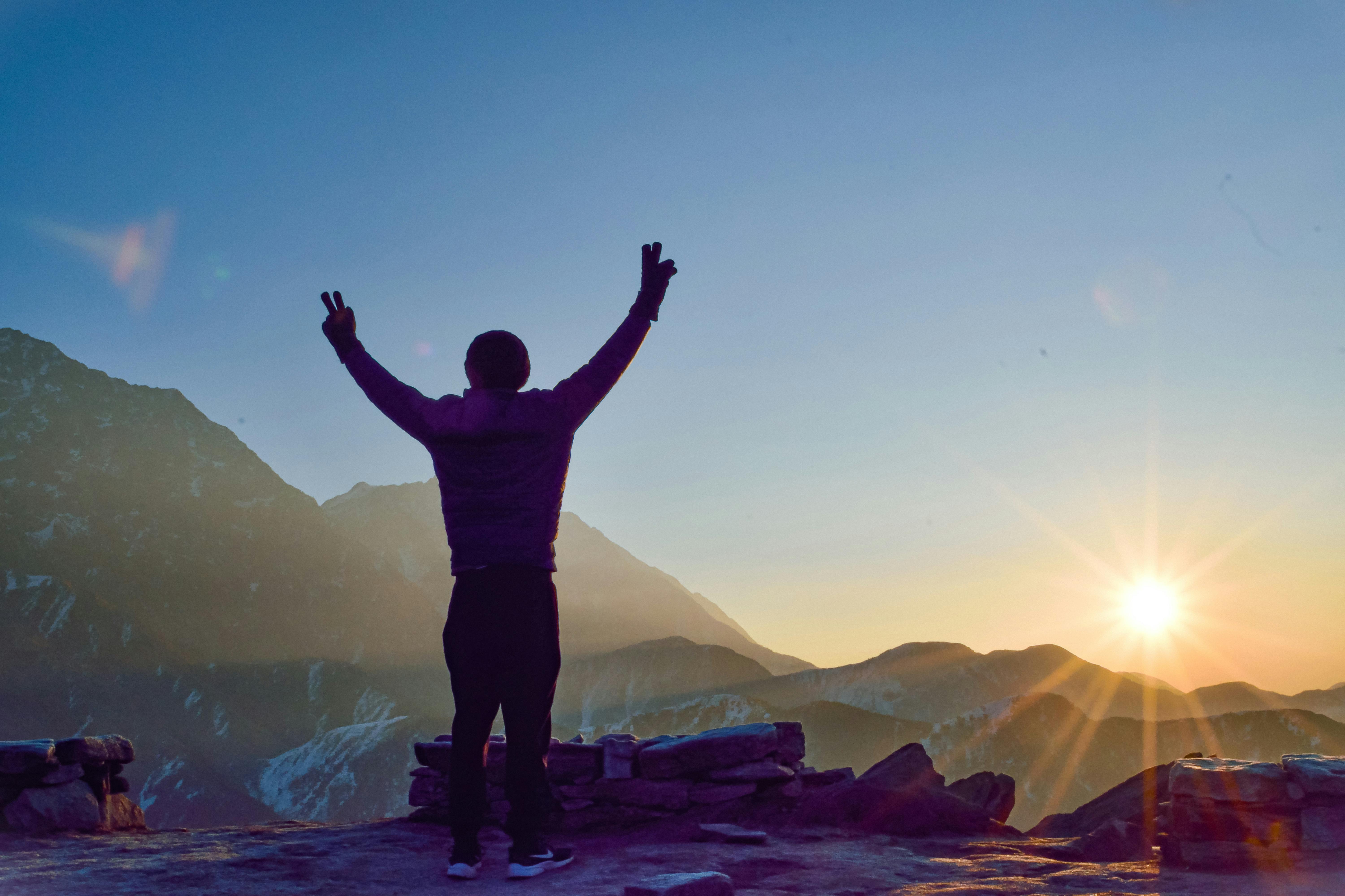 person standing with arms raised in a gesture of victory on a sunlit balcony