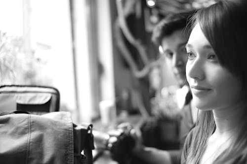 Grayscale Photo of a Woman Being Stared by a Man Inside a Room