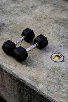 Pair of black hex dumbbells resting on a concrete surface, ideal for strength training and fitness routines.