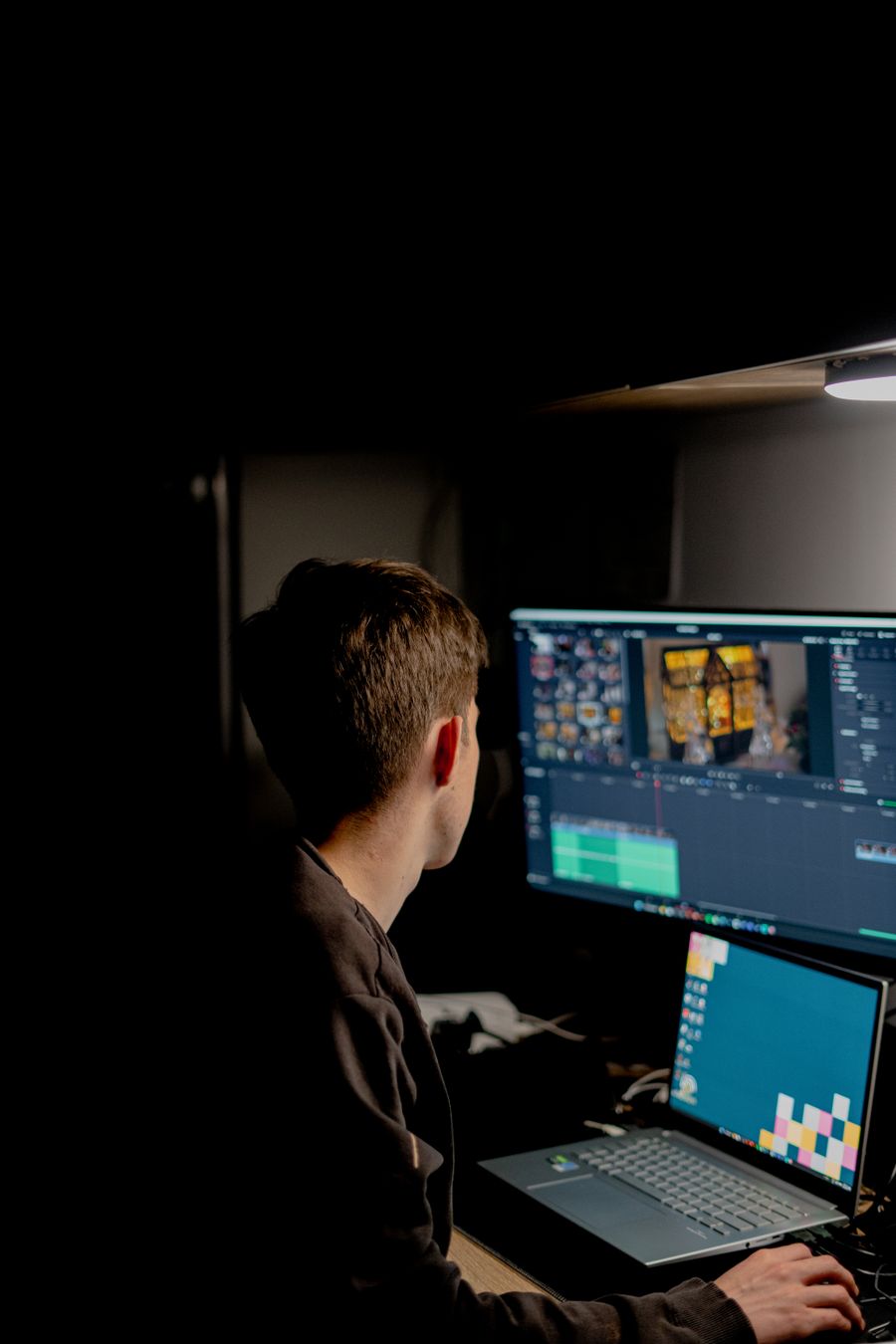 Editor colour grading footage at a darkened suite