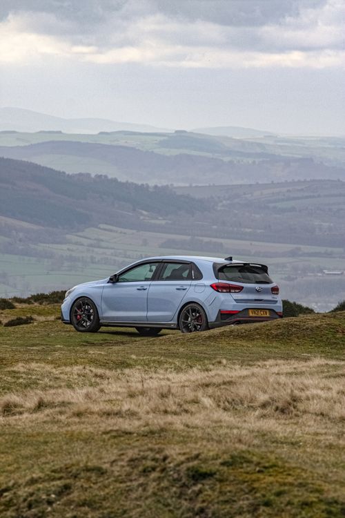 Free White car parked on a scenic meadow with a breathtaking mountain view. Stock Photo