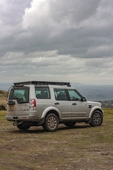 A silver SUV parked on a rocky terrain under a cloudy sky, capturing a sense of exploration.