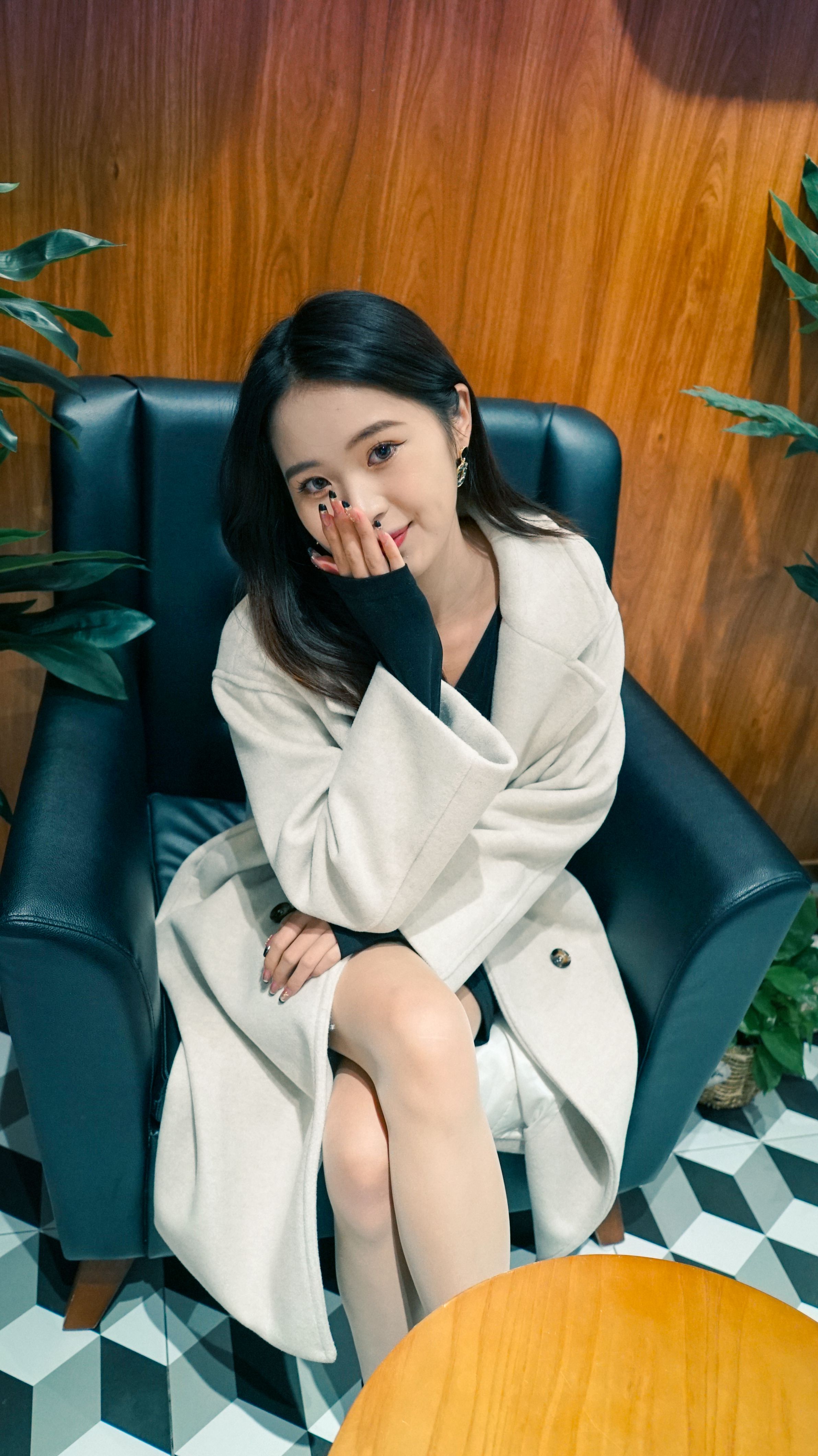 Fashion portrait of a woman sitting on a chair in a stylish indoor setting, exuding elegance.