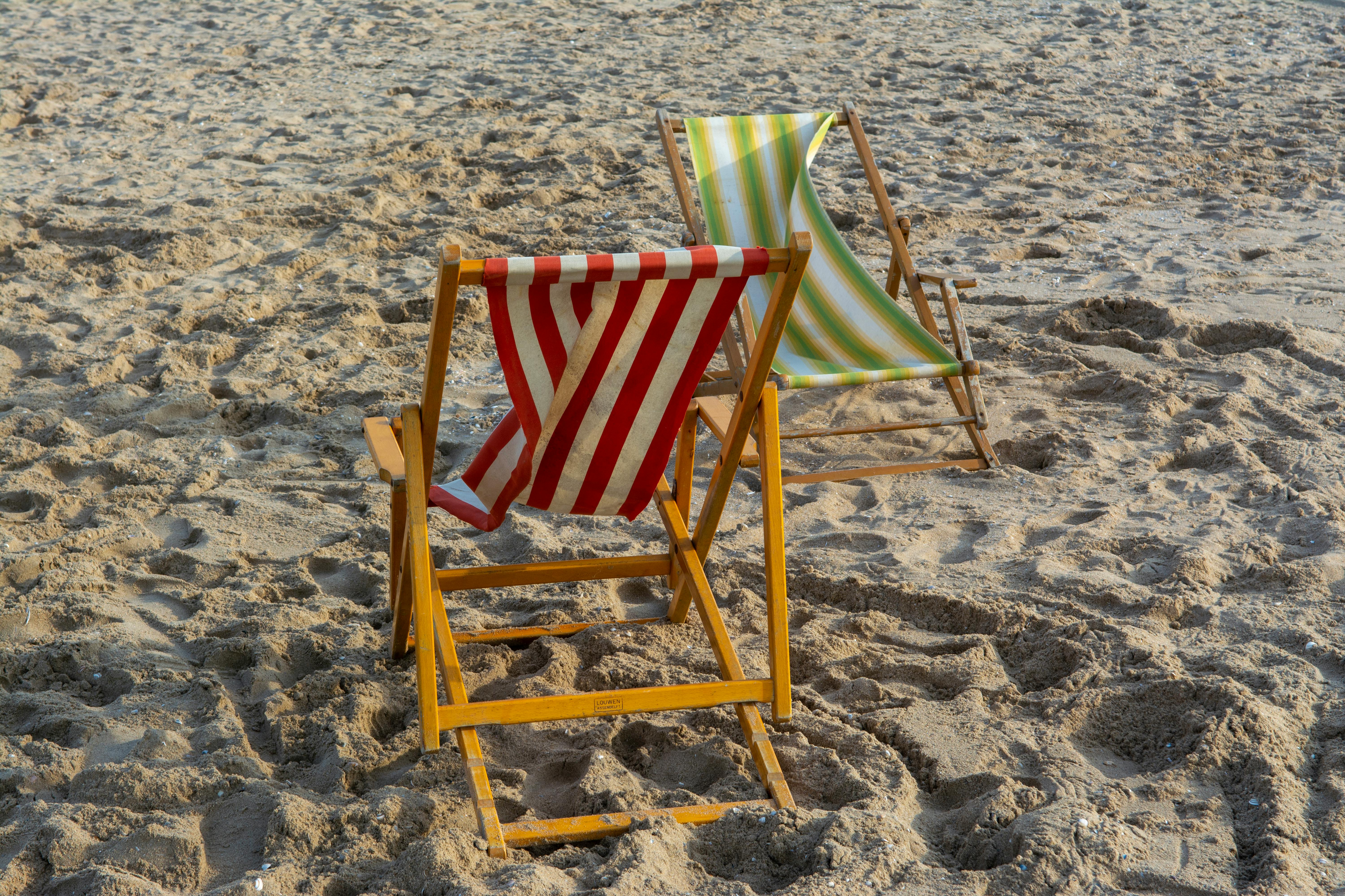 Two striped deck chairs on a sunny sandy beach, perfect for relaxation.