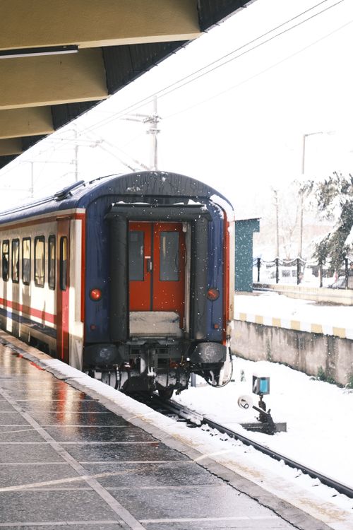 Free Snow-covered train station platform with a departing train in winter scenery. Stock Photo