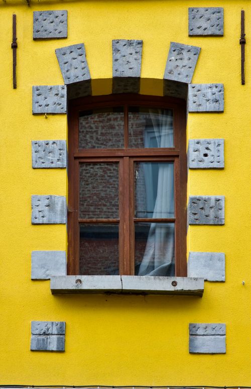 Free Close-up of a traditional window on a vibrant yellow wall in Mons, Belgium. Stock Photo