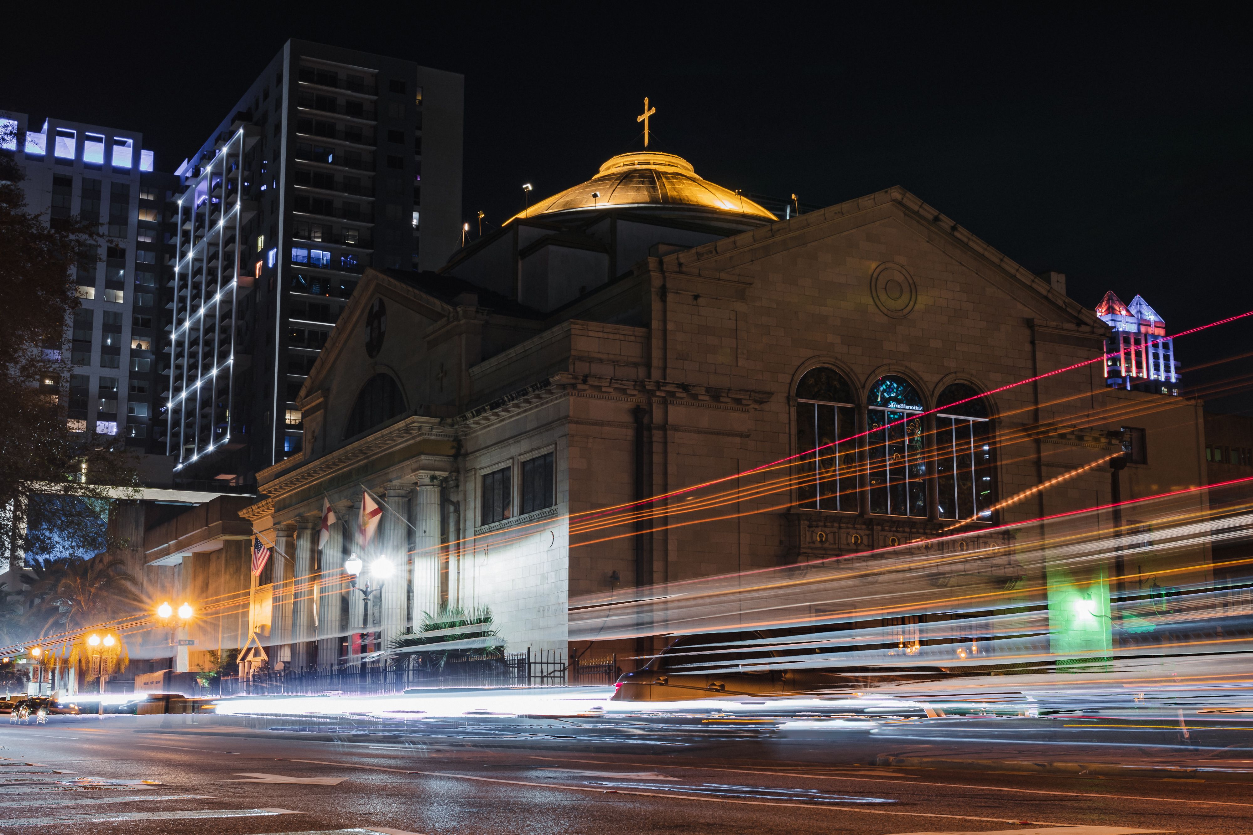 A stunning night view of a church in downtown Orlando with vibrant light trails from passing cars, highlighting urban life.