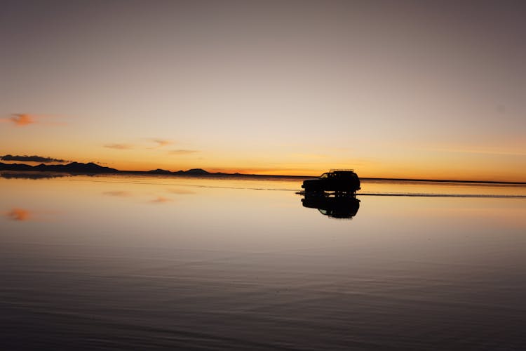 Silhouette Of A Car Driving Through A Salt Flat