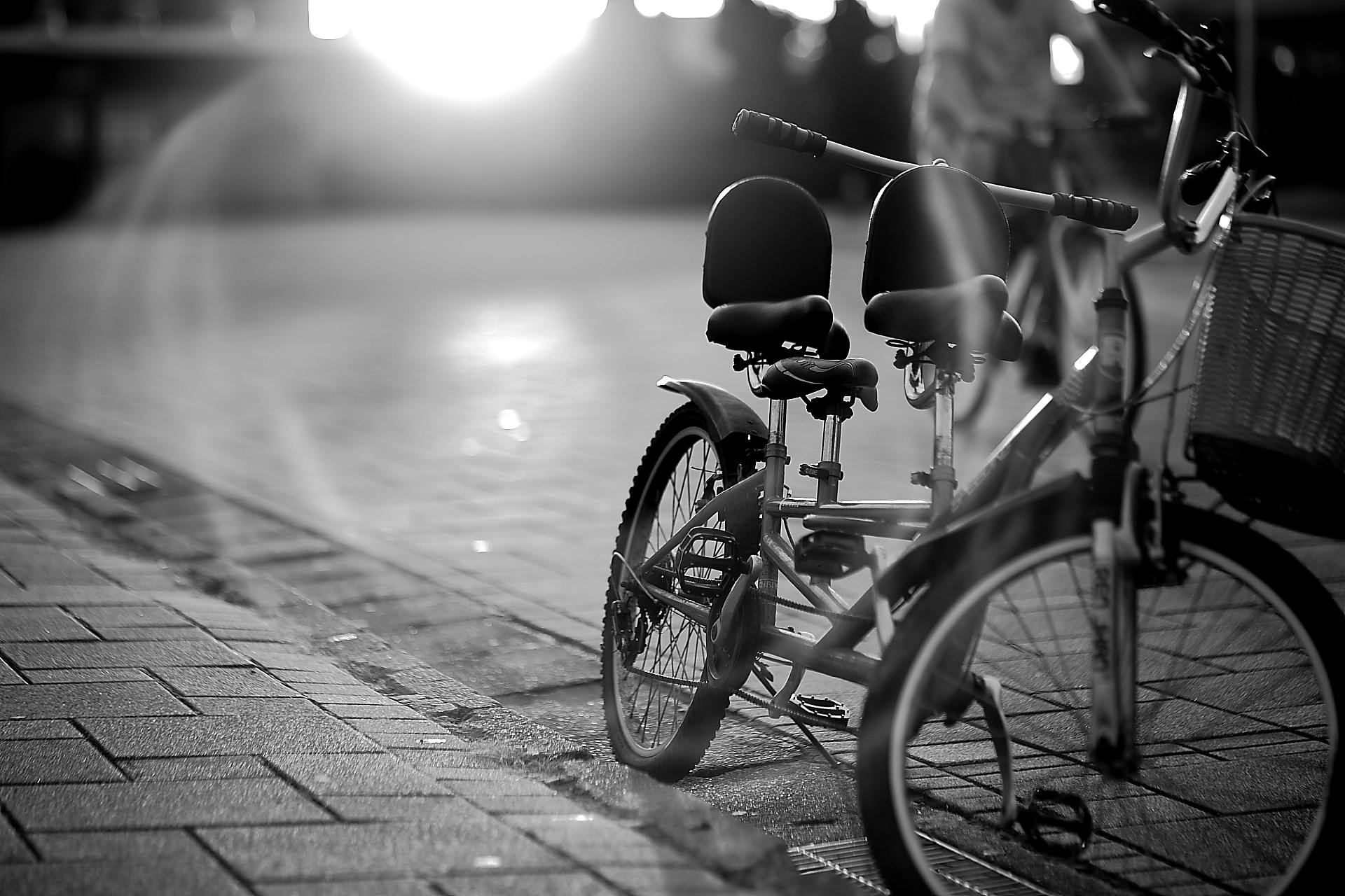 Elegant black and white photo of a tandem bicycle on an urban street with dramatic lighting.