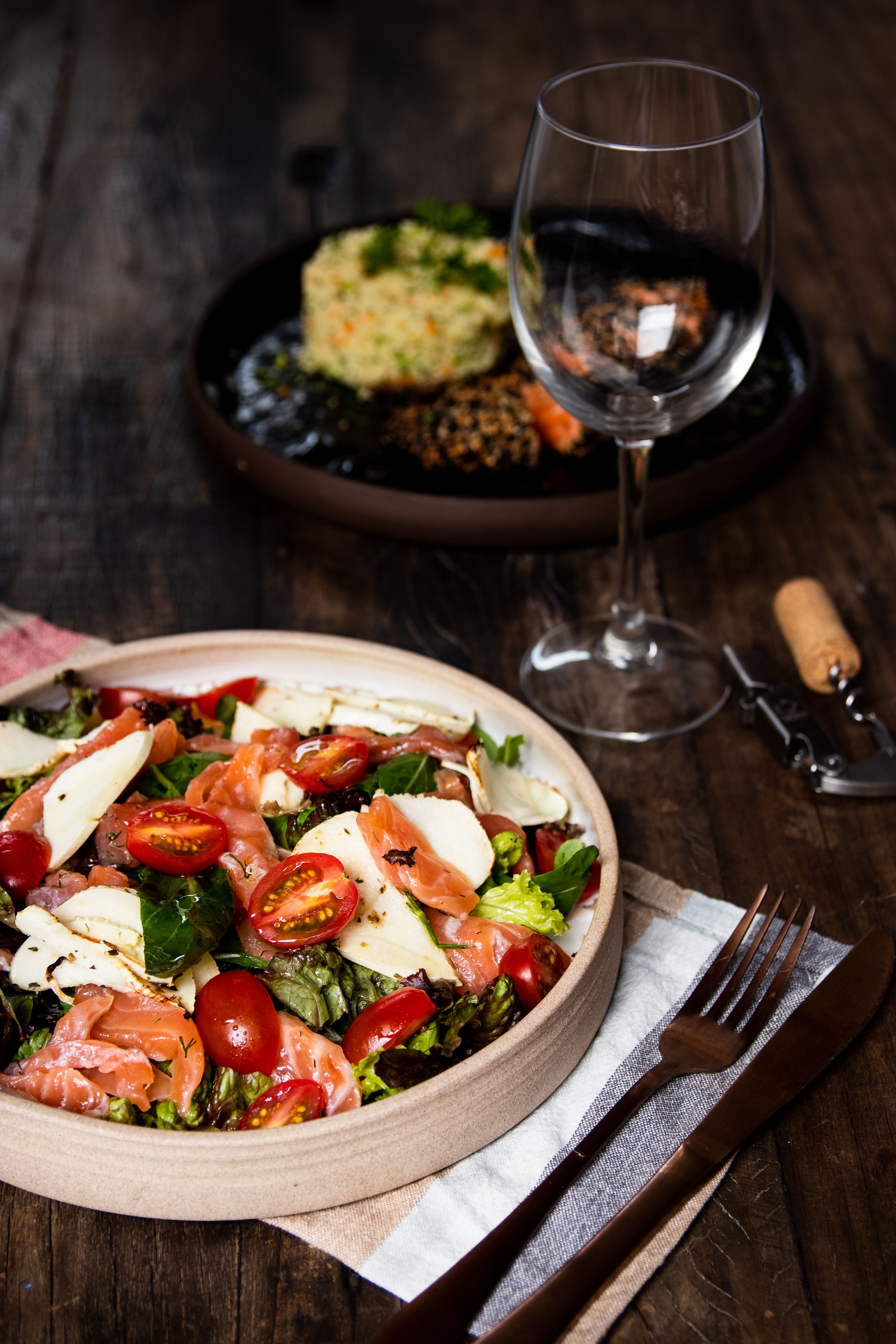 Delicious smoked salmon salad with cherry tomatoes and cheese, paired with an empty wine glass.