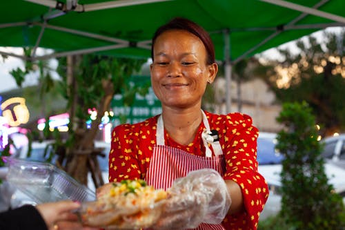 Smiling Woman Selling Food on a Street 