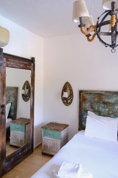 Cozy rustic bedroom featuring a wooden mirror, vintage lamp, and elegant bedding.