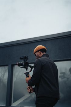 Man using camera gimbal for filming outdoors on a cloudy day.