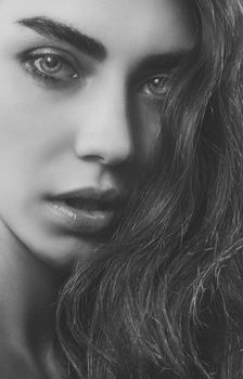 Close-up black and white portrait of a young woman with long hair and striking features.