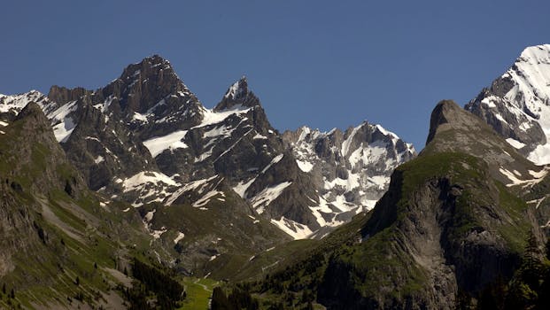 Breathtaking view of rugged snow-covered peaks and vibrant greenery, showcasing nature's grandeur.