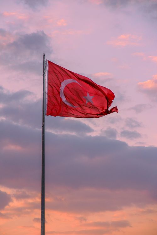 Free National Turkish flag waving at dusk with a vibrant sky background. Stock Photo