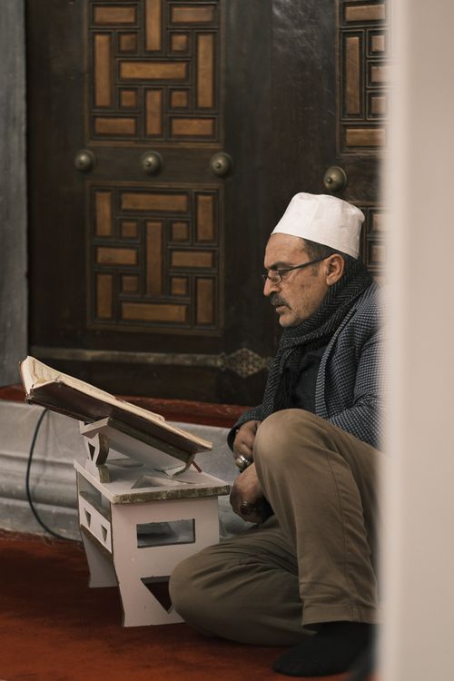 Free Older man reading a book indoors, seated on the floor in a reflective pose. Stock Photo